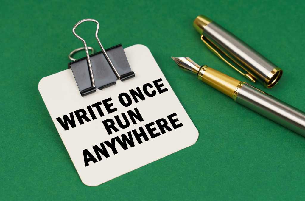 On a green surface, a pen and a sheet of paper with the inscription: Write Once Run Anywhere.