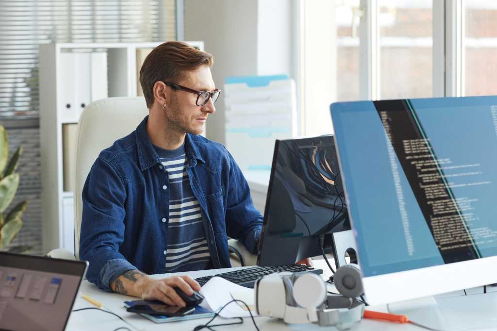 Side view portrait of modern IT developer using computer in office while working on VR games and software, copy space