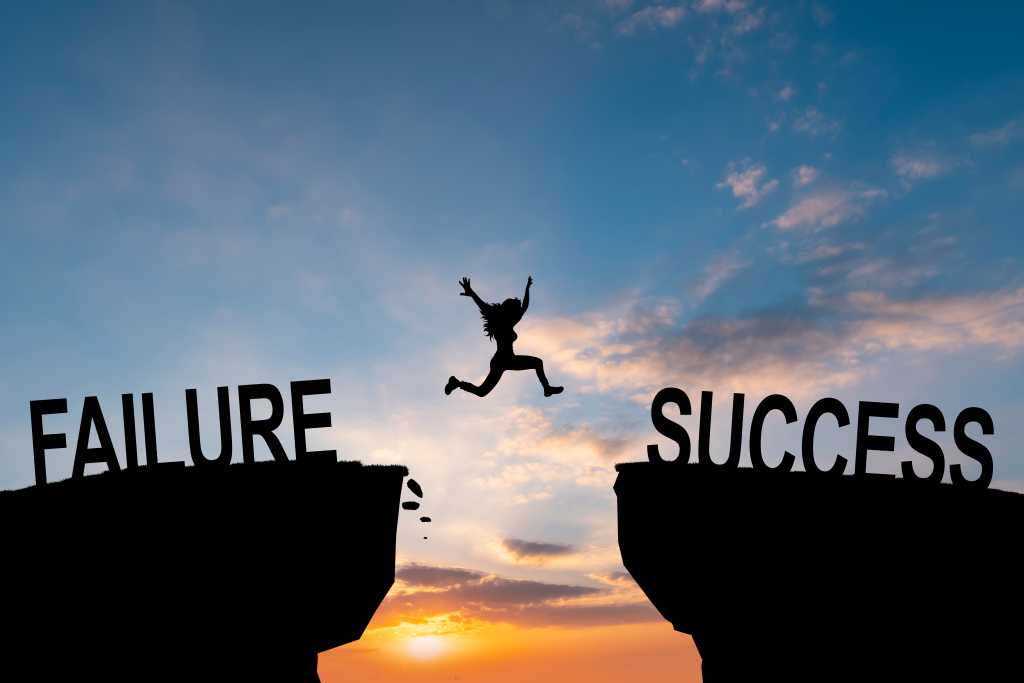 A figure jumps across a mountain chasm with one side marked "failure" and the other "success"
